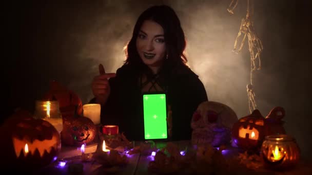 Frau hält Smartphone mit grünem Bildschirm senkrecht und zeigt mit dem Finger darauf — Stockvideo