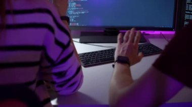 Bilgisayar ekranının önünde oturan ve Javaskript yazan iki programcının takım çalışması