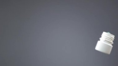 Haplı bir şişe düşer ve saydam yüzeye yavaş çekimde dökülür.