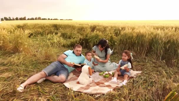 Familie mit zwei Kindern sitzt an der Decke auf dem Roggenfeld beim Picknick — Stockvideo