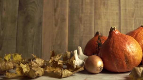 Натюрморт с овощами и сухими листьями за деревянным столом — стоковое видео