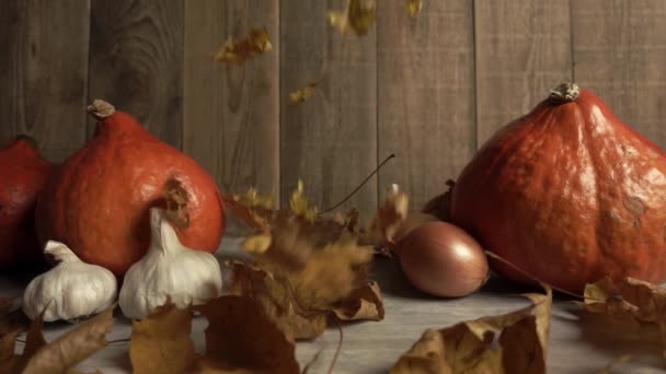 Suché listí padá na podzimní složení z pomerančových dýní a cibule s česnekem ve zpomalení — Stock video