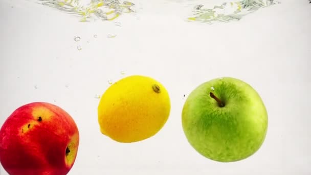 La manzana, el limón y la naranja caen maravillosamente en el agua con burbujas. Frutas de videografía en cámara lenta. — Vídeos de Stock