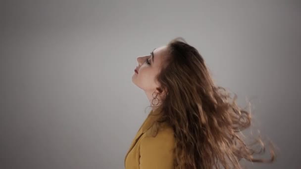Eristetty muotokuva nuori nainen ravistelee päätään pitkät terveet hiukset ja poseeraa — kuvapankkivideo