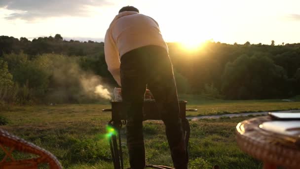 El hombre está cocinando shashlik en el brasero en un día de verano al aire libre en cámara lenta — Vídeos de Stock