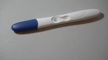 Hamilelik testi beyaz zemin üzerinde yalan söylüyor ve makro olarak pozitif sonuç veriyor
