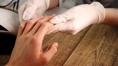 Manicurist holds clients hands with art design and appreciates his work in closeup