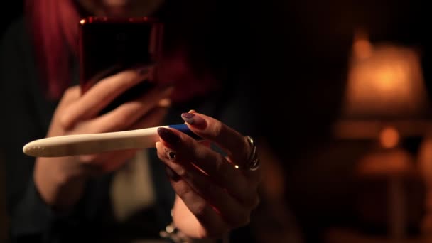 Young woman is holding the pregnancy test and taking photo of it by smartphone in macro — Stock Video