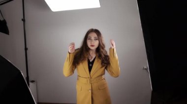 Backstage of professional photoshoot with young pretty woman posing in front of camera in slowmo
