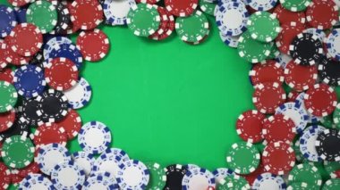Dropping red dice on a green table with poker chips in slowmo filmed from above