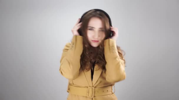 Retrato de uma jovem ouvindo música por fones de ouvido e energia dançando em fundo branco — Vídeo de Stock