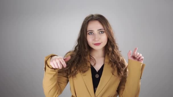 Portrait de femme souriante debout sur un fond blanc et pointant les doigts vers le bas — Video