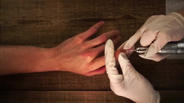 Маникюрша полирует ногти и кутикулу сверлом во время процедуры красоты в салоне, снятом сверху — стоковое видео