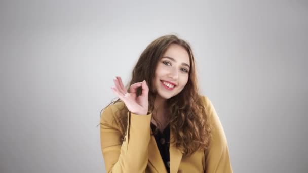 指でok記号を示し、白い背景に笑みを浮かべて若い美しい女性の孤立した肖像画 — ストック動画