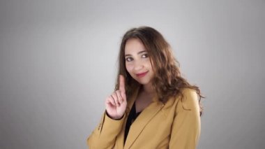 Beyaz arka planda duran işaret parmağıyla hiçbir işaret göstermeyen gülümseyen kadın portresi