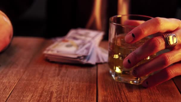 L'uomo in costume nero lancia due dadi rossi e tiene un bicchiere con del whisky in un'altra mano. — Video Stock