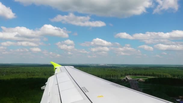 Blick aus dem Fenster eines Flugzeugs, das an einem sonnigen Sommertag in der Stadt landet — Stockvideo