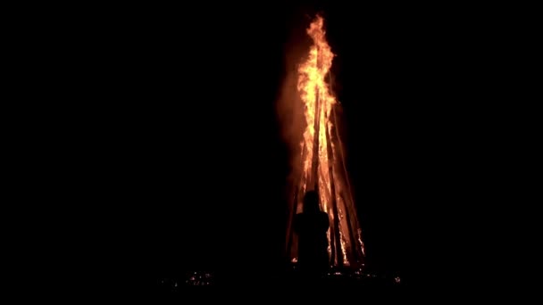 Silhouette of a man who is standing and watching on a big bonfire burning at night in slow motion — Stock Video