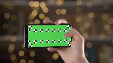 Bokeh arka planına karşı kadın elinde takip işaretleyicileri ile yatay yönelimde mobil