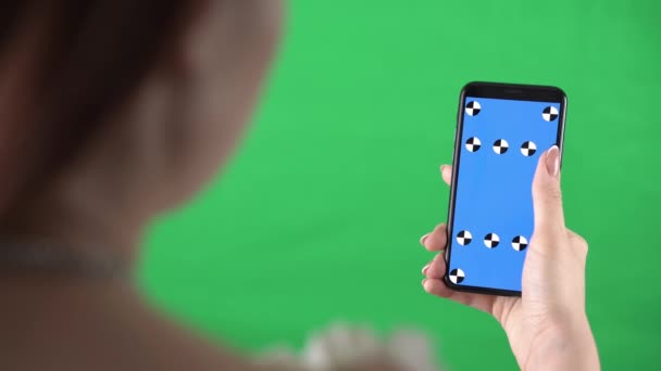 Vrouw met een mobiele telefoon in haar handen schuift pagina 's door vinger met tracking markers op het display — Stockvideo