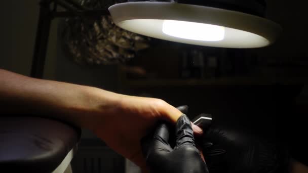 Vrouw in zwart beschermende handschoenen is het maken van manicure naar een man in slow motion en closeup — Stockvideo