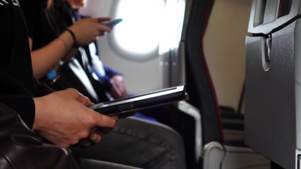 Vista lateral de cerca de las manos de la gente sosteniendo teléfonos inteligentes y sentado en un avión — Vídeos de Stock