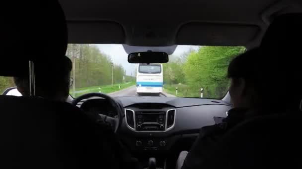 Hombre conduciendo coche en el camino angosto y la mujer sentada a su lado con teléfono inteligente se filma en el interior — Vídeos de Stock