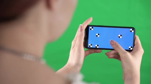 Mulher está ampliando o conteúdo no smartphone com marcadores de rastreamento em exibição e tela verde — Vídeo de Stock