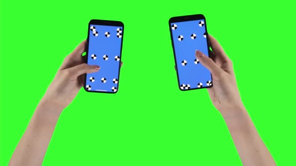 Woman holds two smartphones on green screen background with alpha compositing on displays — Vídeos de Stock