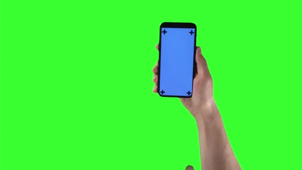 Mann mit Smartphone in der rechten Hand tippt und wischt auf Display mit Tracking-Markern auf Greenscreen — Stockvideo