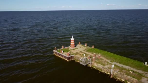 Drone záběry z mola a majáku v oceánu vedle zelené pobřežní čáry — Stock video