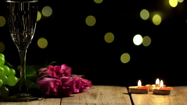 Стол для романтического вечера с виноградом, лежащим рядом с розовыми розами и бокалом шампанского — стоковое видео