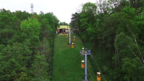 Pista con cabine gialle in movimento tra alberi verdi e montagne è filmato da drone — Video Stock