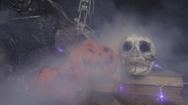 Duman kafatasına üflüyor ve cadılar bayramı balkabakları kitapların önünde duruyor.