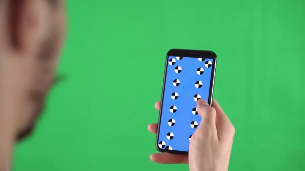 O homem está rolando páginas no smartphone com marcadores de rastreamento em exibição e tela verde — Vídeo de Stock