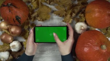 Kadın elinde yeşil ekranlı bir cep telefonu tutuyor ve ekranı tıklatıyor.