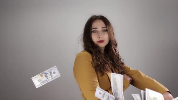 노란 의상을 입은 젊은 여성 이 느림보로 하늘을 나는 현금 사이에서 흰 배경을 취하고 있다 — 비디오