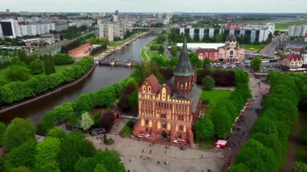 Міський пейзаж з величезним старим собором, розташованим поруч з річкою, і люди, які відвідують його, знімали безпілотник — стокове відео