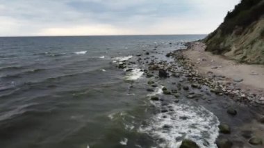 Rüzgarlı ve soğuk bir günde dalgalı deniz ve taşlı kaya insansız hava aracı tarafından filme alınır.