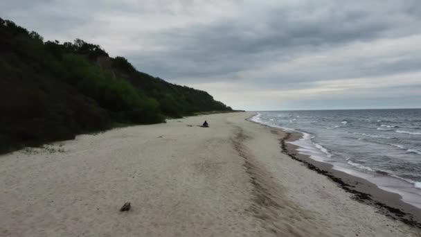 Der Mensch sitzt am Ufer des Ozeans und genießt die Landschaft, die von einer Drohne gefilmt wurde — Stockvideo