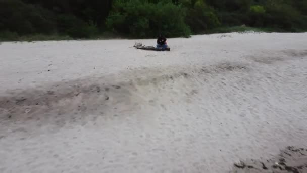 Mann sitzt auf Stein an Küste des Ozeans und fotografiert mit Drohne — Stockvideo