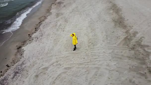 Kvinnan står på stranden av havet och viftar med handen för att drönare kamera filma henne — Stockvideo