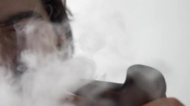 Adam pipo içiyor ve burnundan dumanlar püskürtüyor. Suratı asık.
