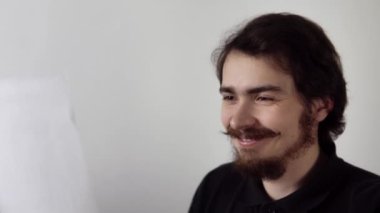 Adam elindeki kâğıt parçasıyla bilgi okuyor ve gülümsüyor sonra mektuba sarılıp mutlu oluyor.