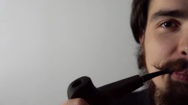 Genç mutlu adam retro tarzı pipo içiyor ve beyaz arka planda gülümsüyor.