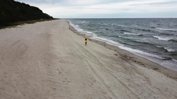 Γυναίκα τρέχει στην παραλία της άμμου κατά μήκος θυελλώδη ωκεανό γυρίστηκε από drone — Αρχείο Βίντεο