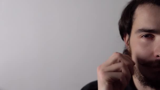 Portret van een jonge man met baard die zijn snor krult en knipoogt op een witte achtergrond — Stockvideo