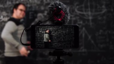 Profesör akıllı telefon ve canlı yayın videoları kullanarak materyalleri açıklıyor.