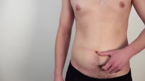 Imagens de close-up de corpo masculino nu magro com barriga gorda e mãos tocando-o no fundo branco — Vídeo de Stock