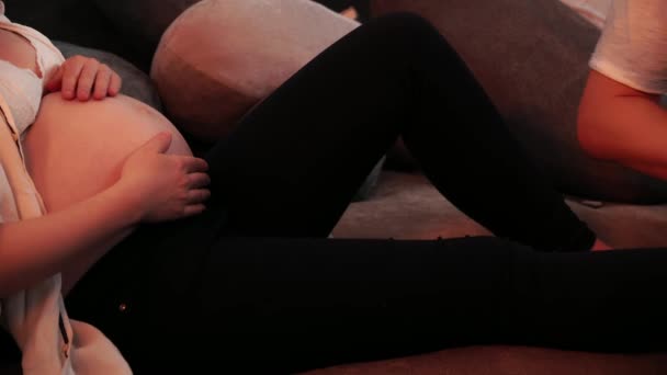 Manžel masíruje nohy své těhotné ženy sedící na pohovce na zblízka — Stock video